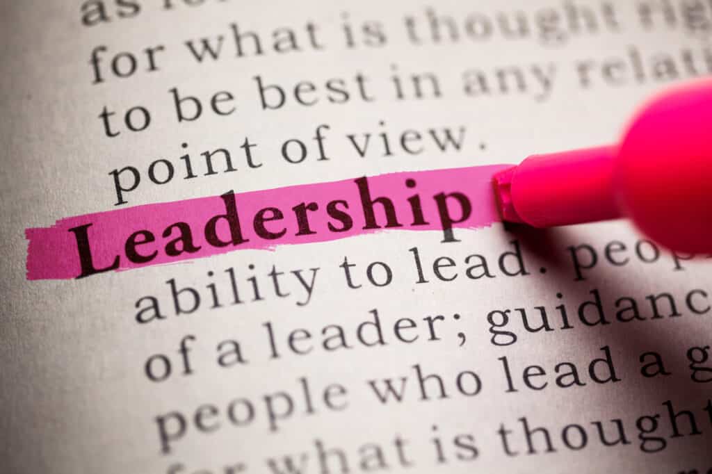 The word Leadership being highlighted in a book by a marker